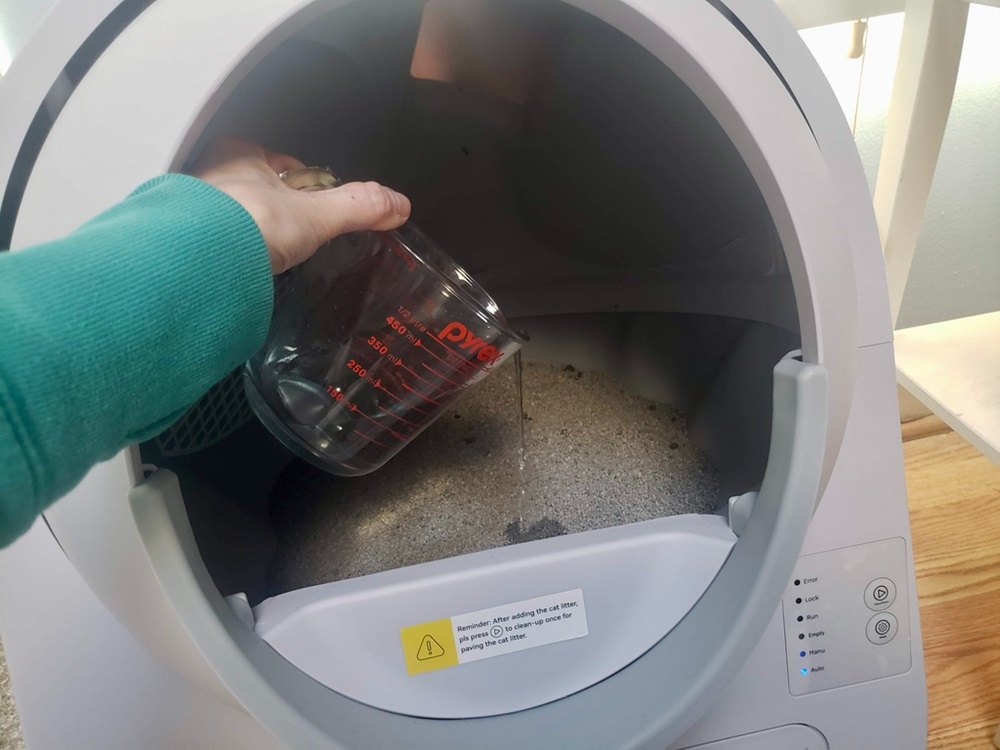 tester pouring water into the litter box to simulate cat pee